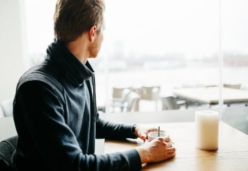 man-with-coffee-looks-out-into-distance-mental-wellbeing