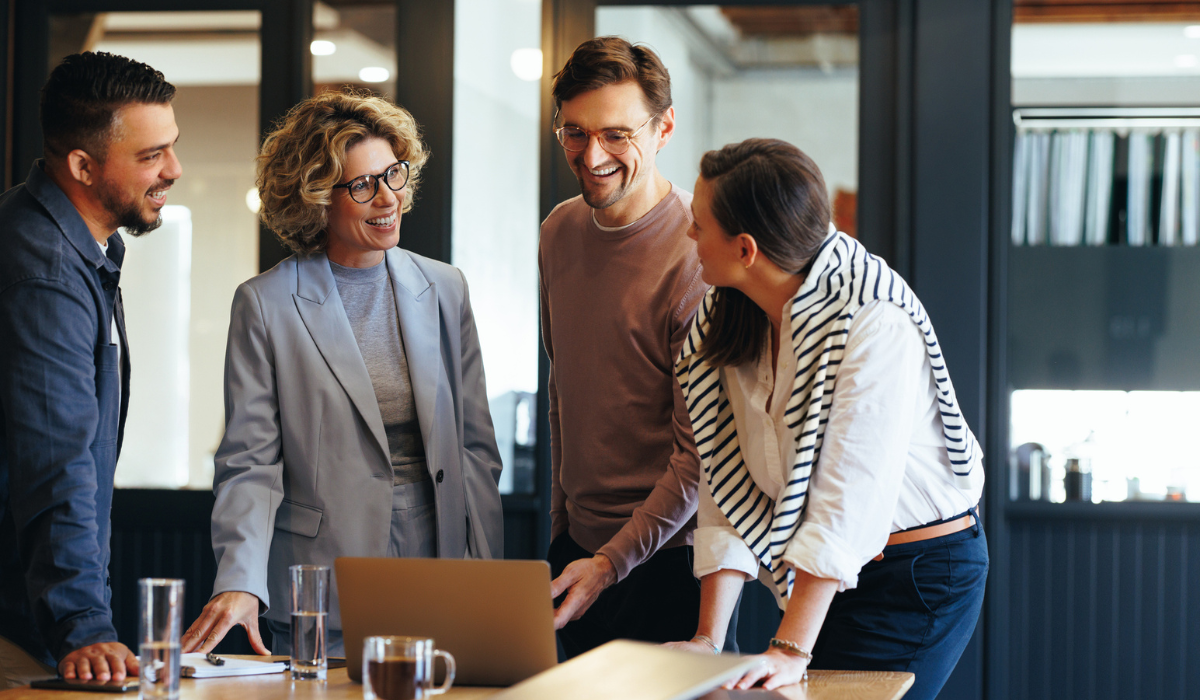 Employees gathered around table talking and smiling