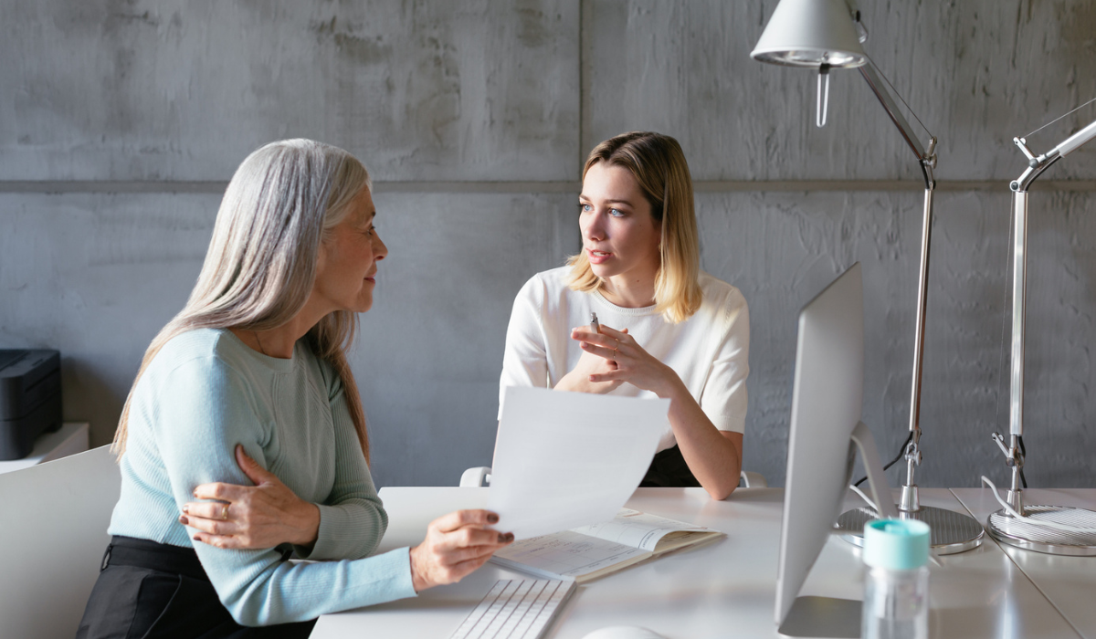 Two female employees sat at a desk talking