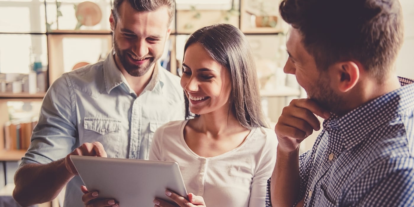 employees-smiling-at-wellbeing-data-on-tablet