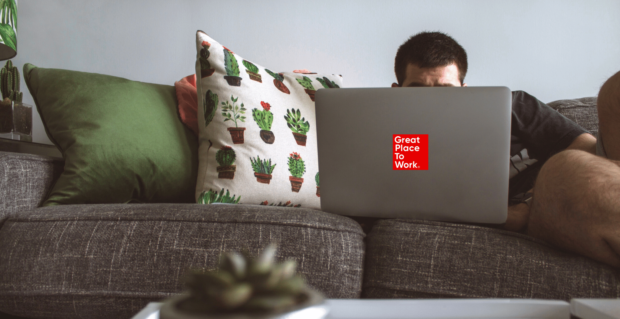 man-with-laptop-no-face-working-on-counch-with-cactus-cushion