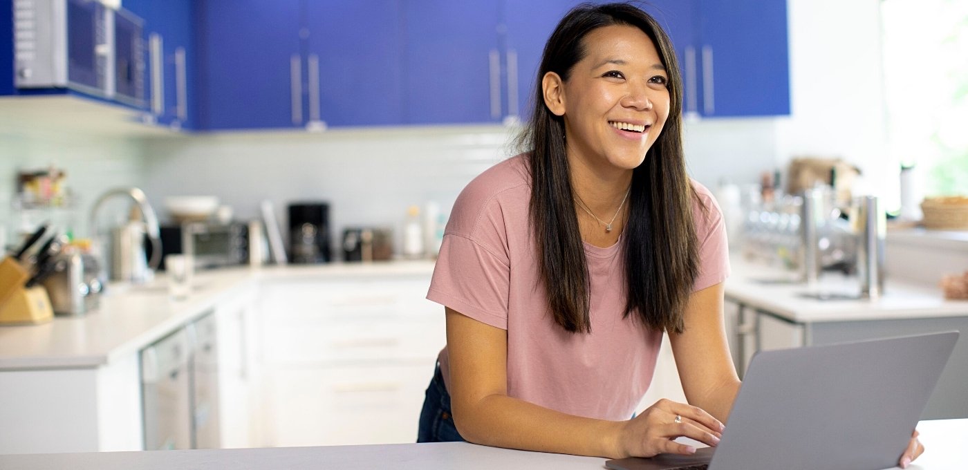 woman-in-kitchen-smiling-remote-onboarding-laptop